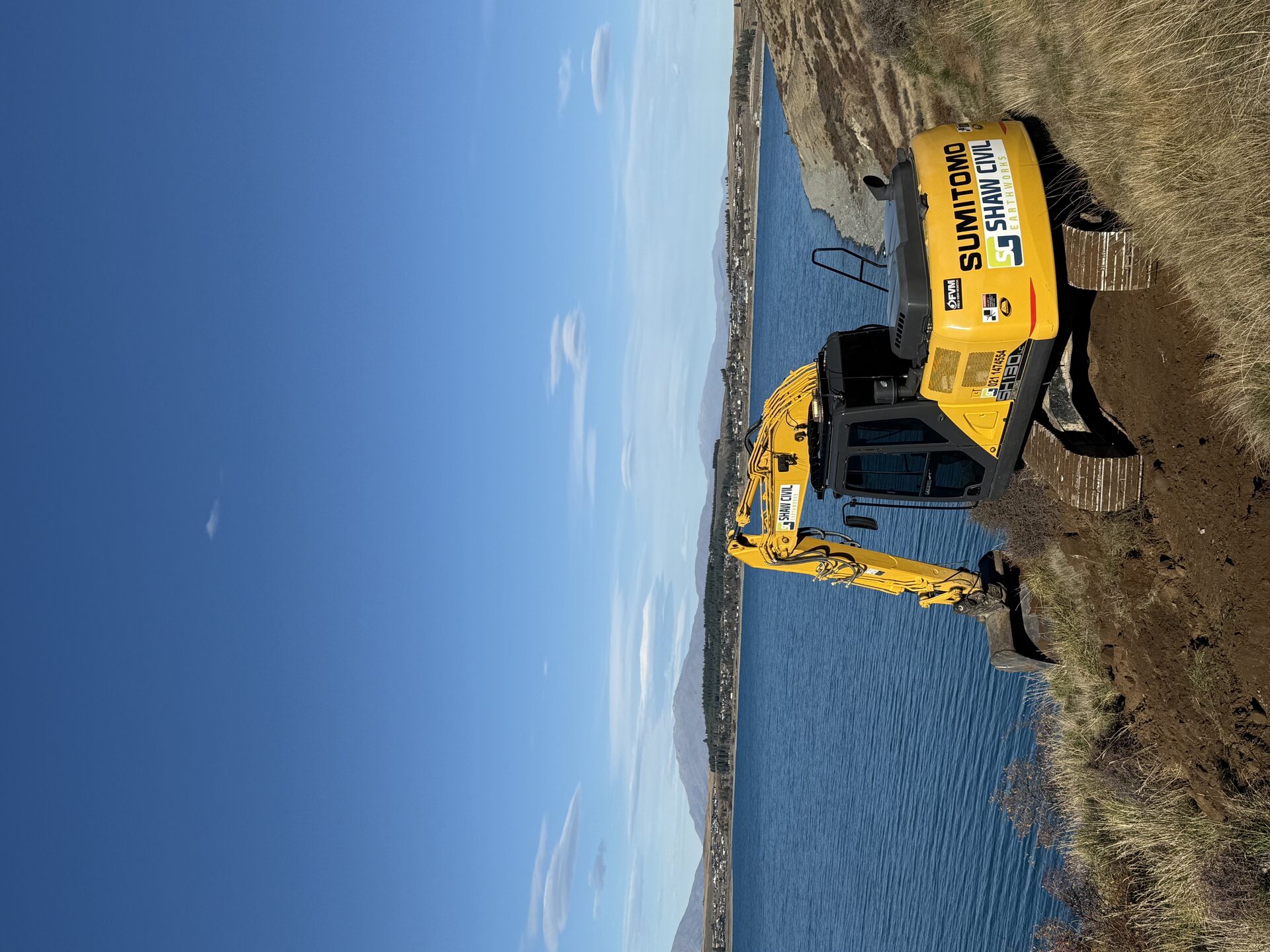 Shaw Civil excavator working beside a lake in the Mackenzie